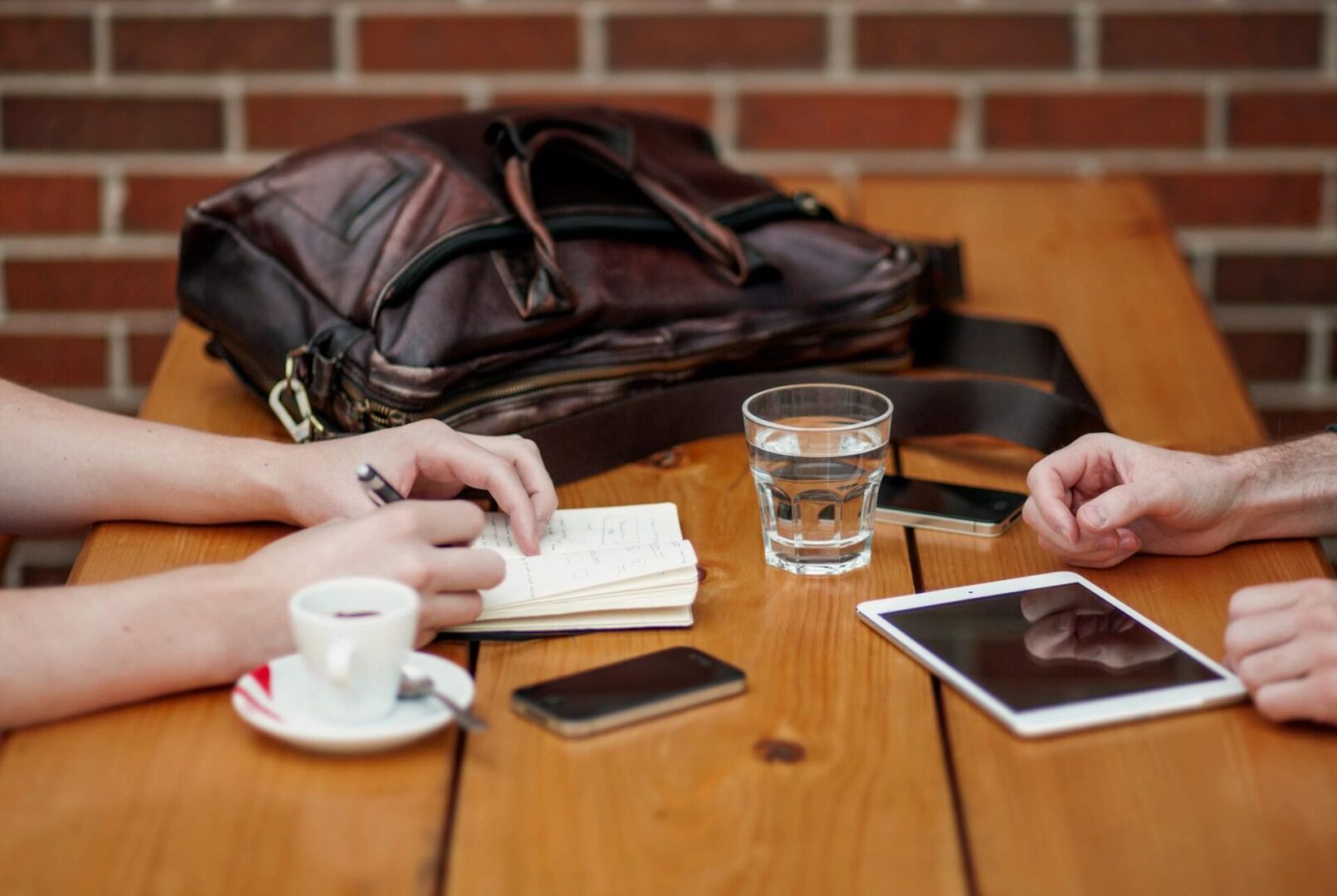 Two people having coffee with bag and other items on table